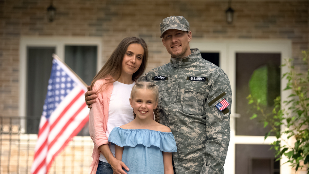 Military family smiling in front of a house