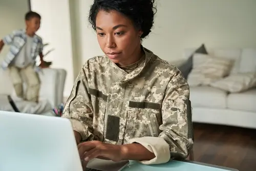 military woman designates her life insurance beneficiary on a computer
